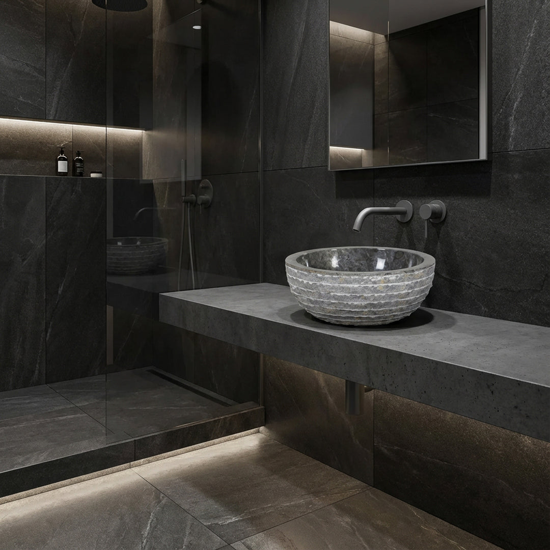 Vasque ronde à poser en pierre sur console flottante, salle de bain moderne avec carrelage foncé, douche en verre et lumière indirecte