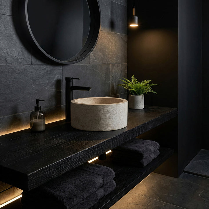 Lavabo à poser rond au look marbre élégant sur une console en bois sombre, mis en scène dans une salle de bain minimaliste à l'ambiance sombre.