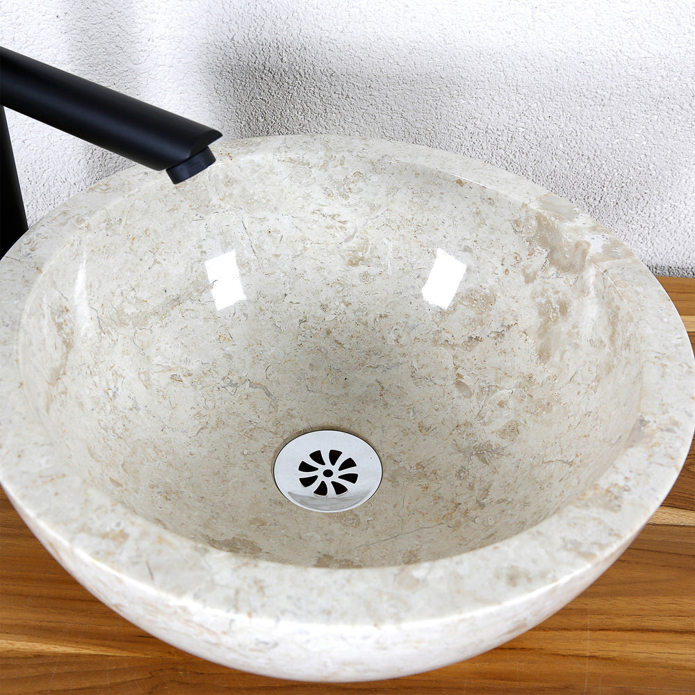 Vue détaillée d'un lavabo à poser rond en pierre naturelle claire avec surface intérieure polie et drain central