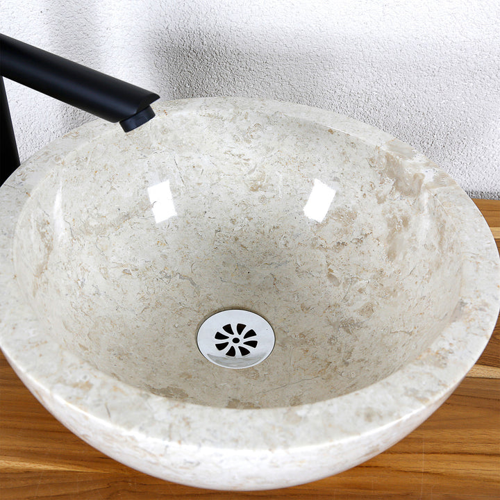 Vue détaillée d'un lavabo à poser rond en pierre naturelle claire avec surface intérieure polie et drain central