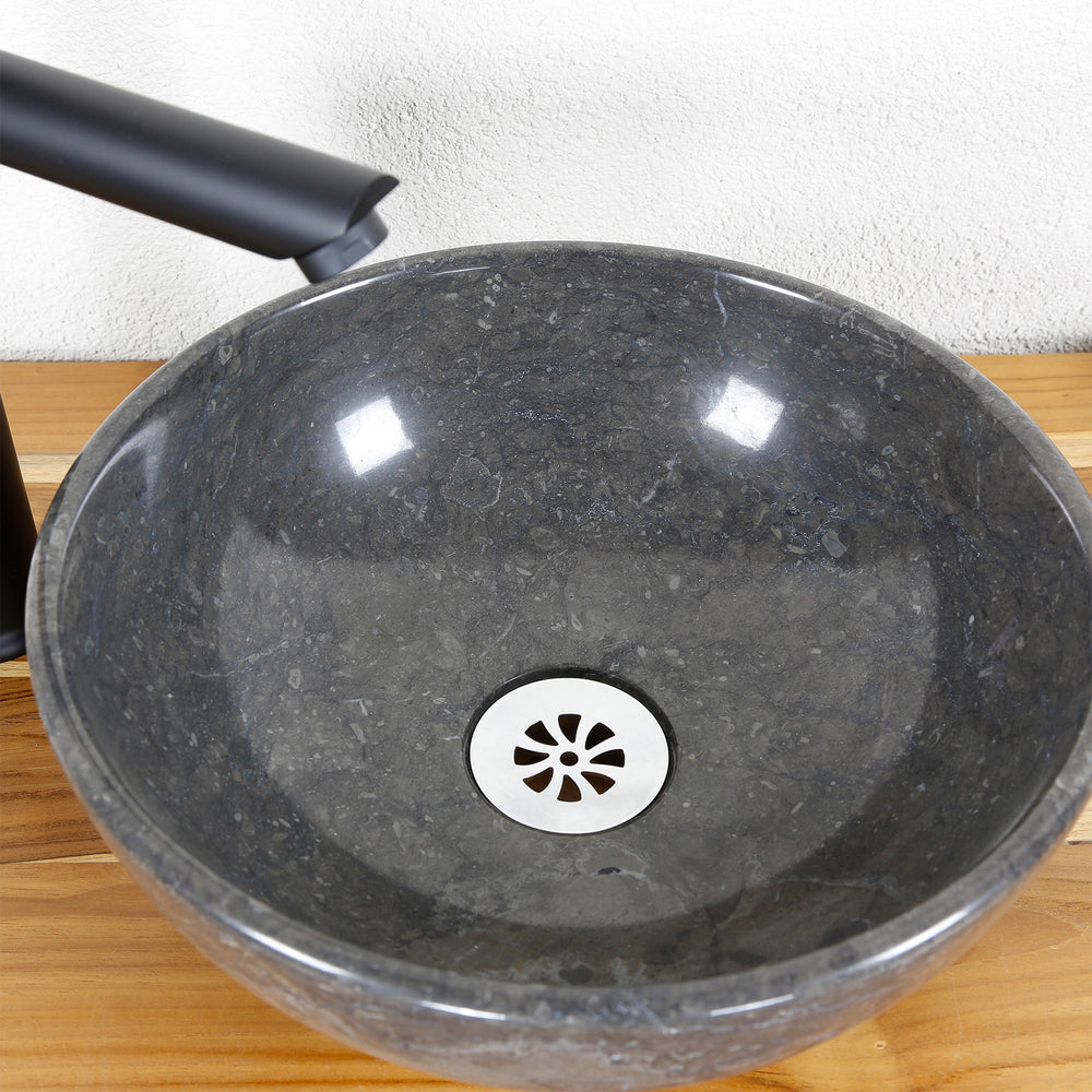 Vasque à poser ronde en pierre naturelle en détail avec surface intérieure polie, vidage et robinetterie en acier inoxydable