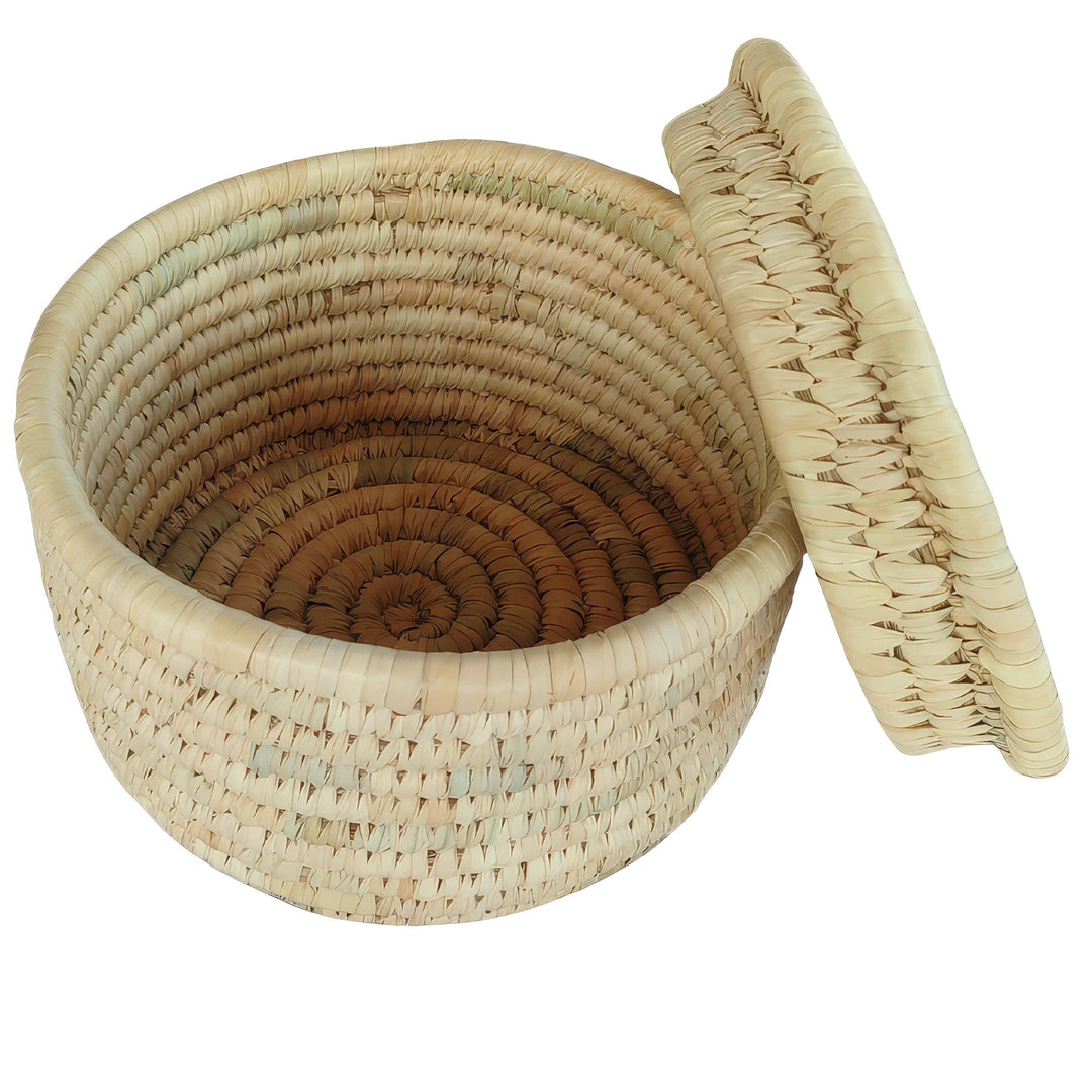 Panier rond tressé en feuilles de palmier, d'un diamètre de 28 cm, avec un couvercle posé sur le côté et un intérieur visible.