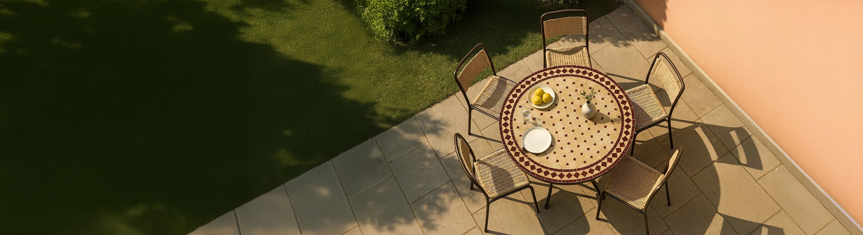 Tables mosaïque Ø100 – Großer runder Mosaiktisch Ø100 cm mit Zellige-Fliesen und mehreren Stühlen auf Terrasse im Garten aus der Vogelperspektive mit warmem Sonnen