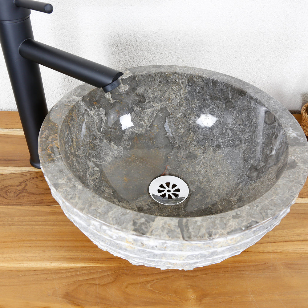 Vasque à poser ronde en pierre naturelle avec surface intérieure polie et bord extérieur structuré sur un plateau en bois