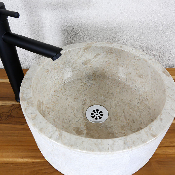 Vue détaillée d'un lavabo à poser rond d'aspect marbre clair avec une surface intérieure lisse et un écoulement fin.