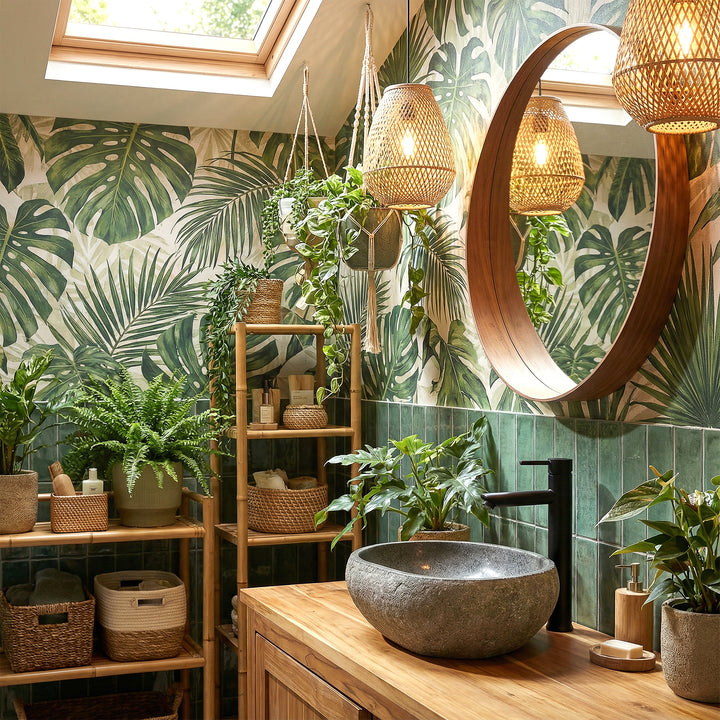 Bassin de comptoir en pierre de rivière dans une salle de bains spa verte sur meuble sous-vasque en bois, combiné avec des raccords noirs et une ambiance végétale