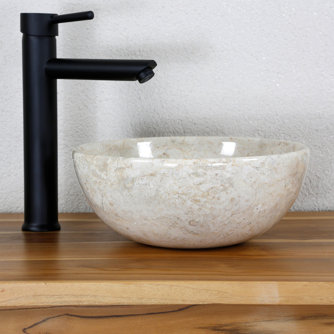 Lavabo à poser en marbre brillant sur un plan en bois avec une robinetterie noire dans un décor de studio clair et minimaliste