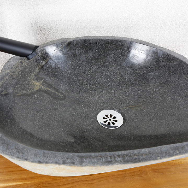 Vue détaillée d'un bassin en pierre avec une surface intérieure finement polie, un grain naturel et un drain central