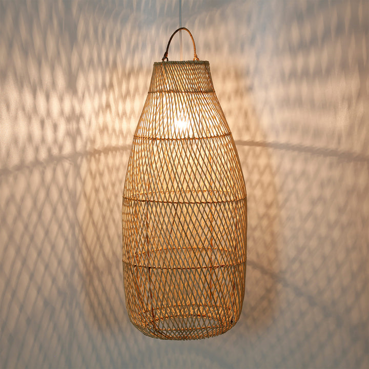 Hohe Rattanlampe mit feinem Flechtmuster und warmem Lichtspiel an der Wand