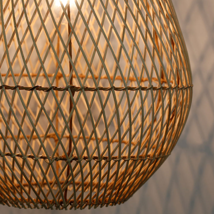 Detailaufnahme einer handgefertigten Rattanlampe mit feinem, diagonalem Flechtmuster und warmem Lichtschein