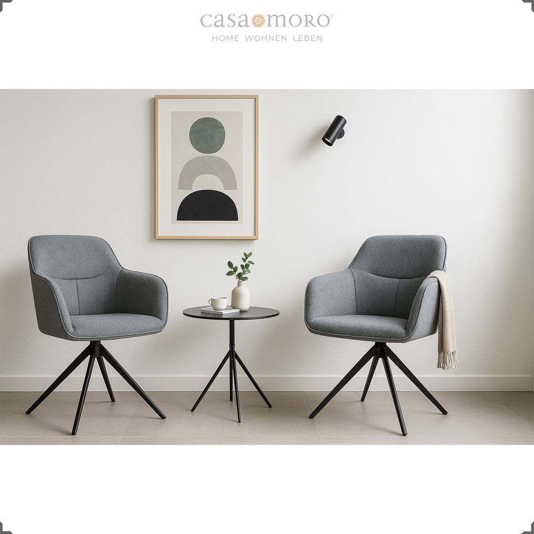 Zwei 360° drehbare Polsterstühle mit Armlehnen in Grau neben einem runden Beistelltisch in modernem Wohnraum mit heller Wanddekoration