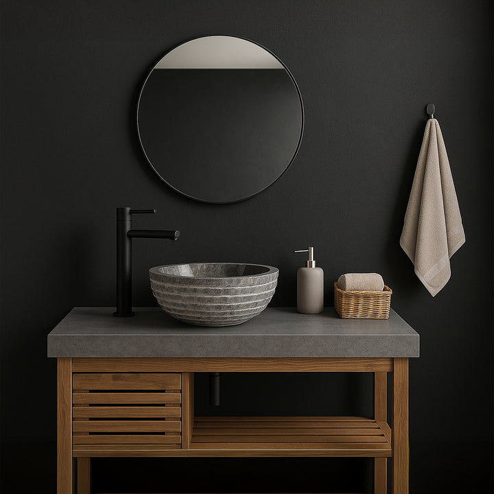 Lavabo en pierre grise comme lavabo à poser sur le meuble sous-vasque, salle de bains moderne avec murs sombres, miroir et accessoires noirs