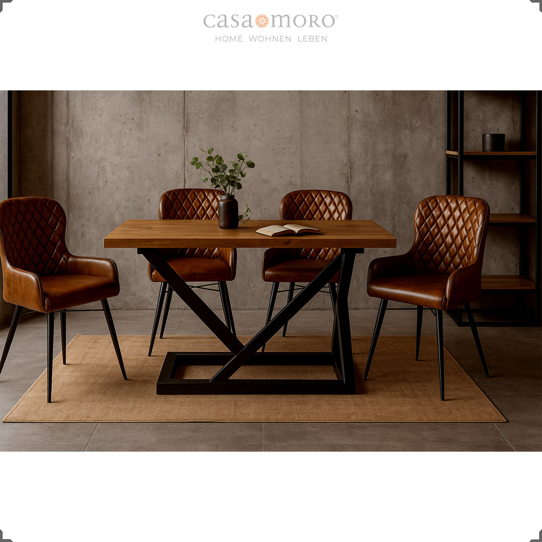 Vier antikbraune Lederstühle mit Rautensteppung an einem modernen Holztisch mit schwarzem Metallgestell in elegantem Loft-Esszimmer mit Betonwand.