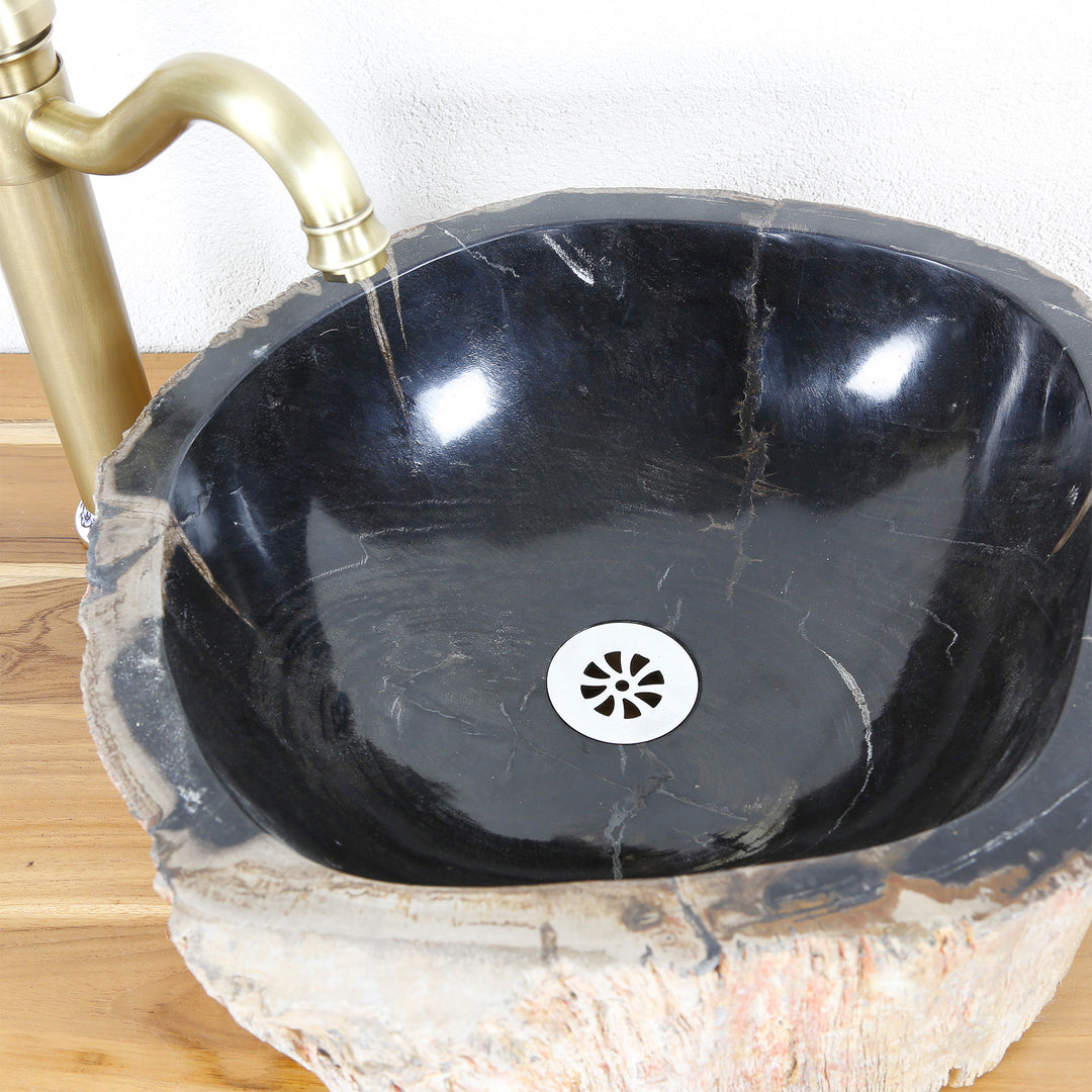 Évier en pierre en bois pétrifié avec surface intérieure polie foncée, vue de dessus avec drain et raccord en laiton sur plateau en bois.