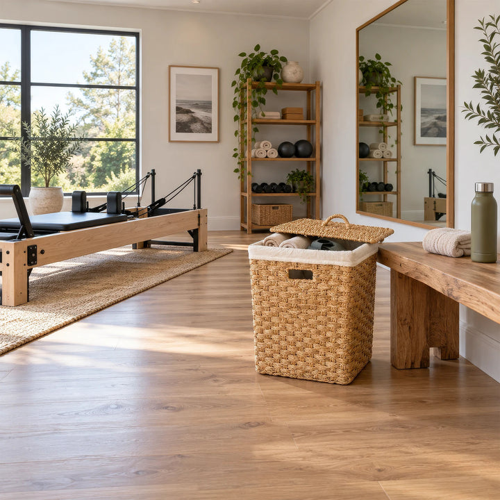 Eckiger Wäschekorb aus Seegras, ca. 85 Liter, mit Handtüchern und halb geöffnetem Deckel neben einer Bank im Pilatesraum.