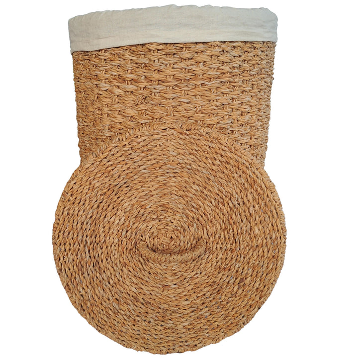 Panier à linge en jonc de mer de couleur naturelle, avec un empiècement en tissu clair et un couvercle posé devant.
