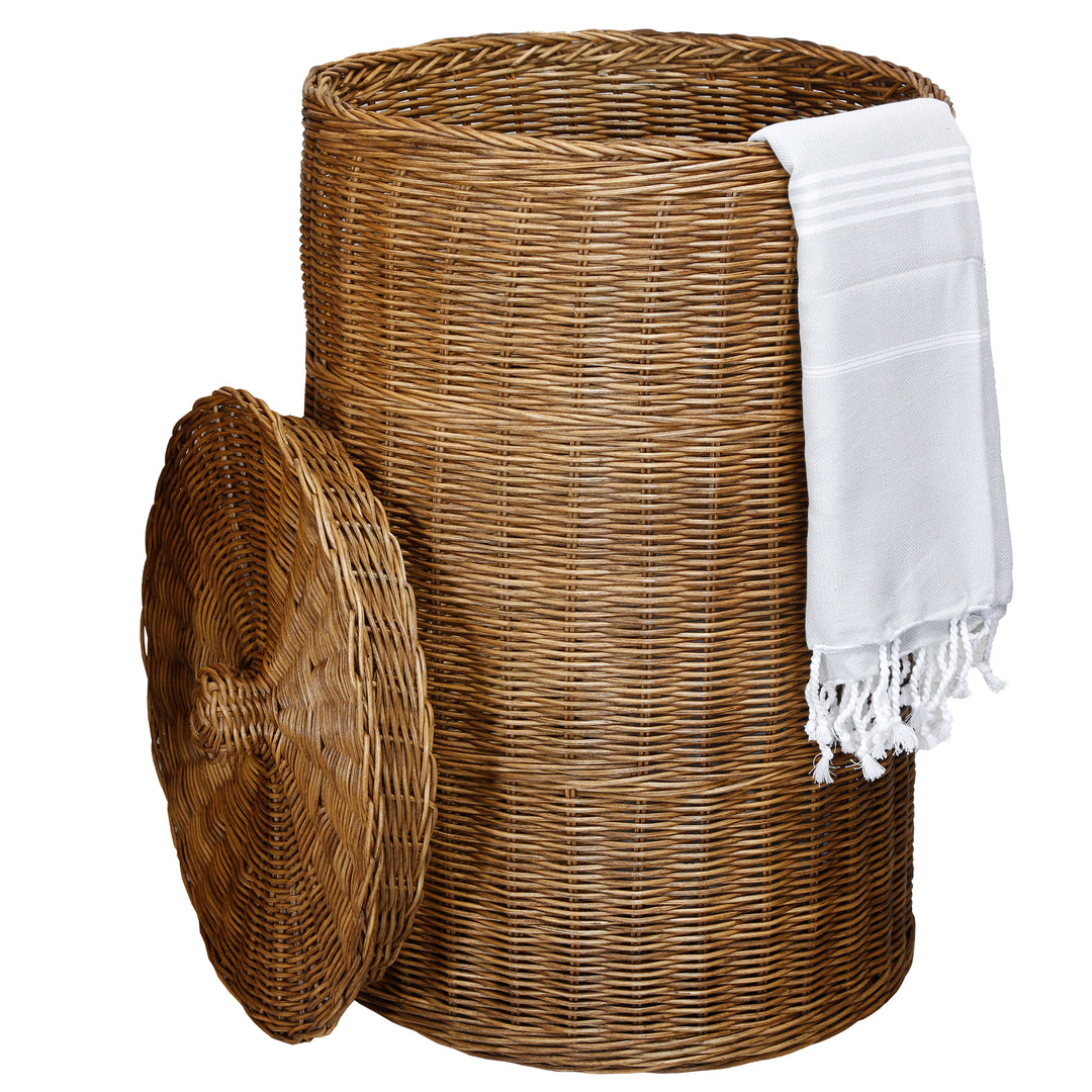 Panier brun en rotin ouvert sans sac intérieur, avec linge blanc sur le bord et couvercle appuyé sur le côté