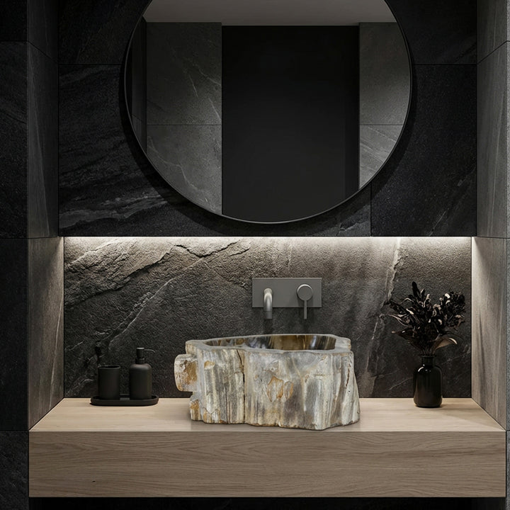 Lavabo en pierre comme lavabo à poser, ambiance de salle de bain moderne avec carrelage en pierre naturelle sombre, lignes claires et éclairage subtil.