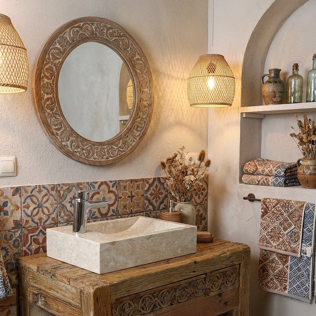 Lavabo rectangulaire à poser en pierre naturelle claire sur un lavabo en bois dans une salle de bains orientale avec carrelage à motifs et lumière chaude